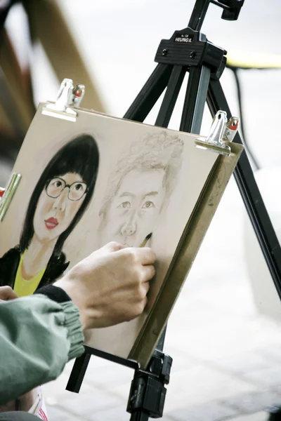 Straßenkünstler zeichnet Porträt von Menschen — Stockfoto