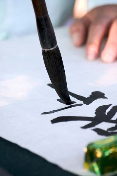 Человек пишет кисточками
