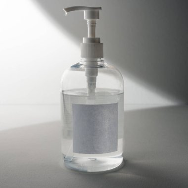 Beyaz ve gri arkaplan üzerine el dezenfektanı sabunu ve boş etiket.