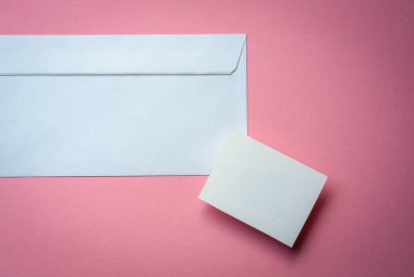 beyaz kartvizitle pembe arka planda beyaz zarf. Tasarım alanınız için kopyalama alanı .