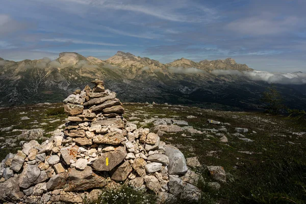 Stone cairn or way marker with peaks in background in Alps, France