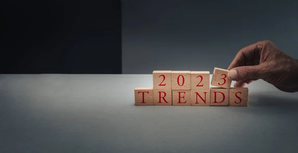 concept of trends for 2023 ,hand posing blocks on blue grey background with copy space .