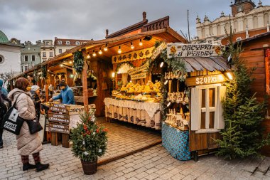 Krakow, Polonya-17 Aralık 2021 Ana Meydanı 'ndaki ünlü Noel pazarı, Rynek Glowny, dumanlı peynir, sıcak şarap ve diğer Polonya spesiyalleriyle süslenmiş kereste kulübeleri..