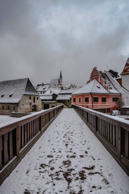 Vltava nehri boyunca ahşap yol, arka planda binalar ve kilise Cesky Krumlov, Çek Cumhuriyeti. Kış bulutlu bir gün, turist olmayan boş bir cadde. Ünlü ortaçağ kasabası, UNESCO mirası..