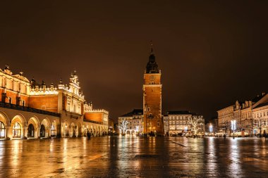 Krakow after rain,Poland.Main square with famous Christmas markets,Rynek Glowny at night with reflection,decorated timber huts,Xmas tree.Festive atmosphere,blurred people in motion,illuminated city.