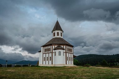 Small white rural Tesarovska chapel with cemetery in village of Korenov, Jizera mountains, Czech Republic. Summer landscape, stormy sky.Wooden historic church. Religious scenery.Czech countryside.