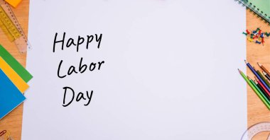 Beyaz kağıt üzerinde, ahşap masadaki çoklu okul ekipmanlarına karşı mutlu çalışma günü mesajları. İşçi bayramı konsepti