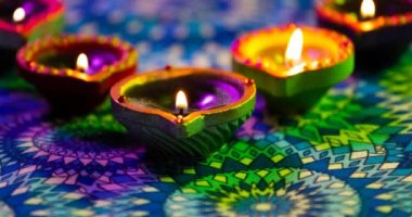 Mor ve yeşil desenli yüzeyde parlayan diwali mumlarının videosu. diwali, ışık festivali, yeni yıl, gelenek ve kutlama konsepti.