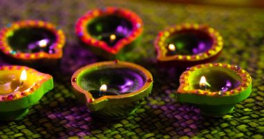 Dokuma mor ile yeşil yüzey arasında daireler çizerek parlayan diwali mumlarının videosu. diwali, ışık festivali, yeni yıl, gelenek ve kutlama konsepti.
