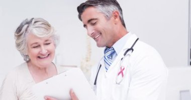 Kafkasyalı yaşlı kadın ve erkek doktor yerine pembe kurdeleli umut animasyonu. Göğüs kanseri pozitif farkındalık kampanyası konsepti dijital olarak üretildi.