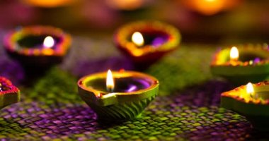 Dokuma mor ile yeşil yüzey arasında parlayan diwali mumlarının videosu. diwali, ışık festivali, yeni yıl, gelenek ve kutlama konsepti.