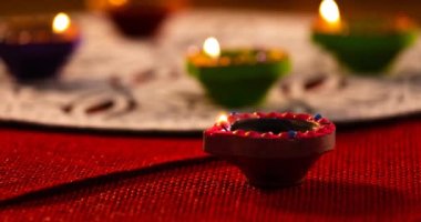 Kırmızı ve beyaz desenli yüzeyde parlayan diwali mumlarının videosu. diwali, ışık festivali, yeni yıl, gelenek ve kutlama konsepti.