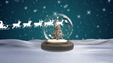 Kar küresindeki Noel ağacına karşı ren geyikleri tarafından çekilen kızaklı Noel Baba. Noel şenliği ve kutlama konsepti