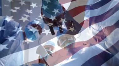 Ameliyathanede cerrahların üzerinde sallanan ABD bayrağının animasyonu. küresel tıp, covid 19 pandemik konsept sırasında sağlık hizmetleri dijital olarak üretilen video.