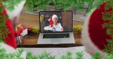 Noel Baba ve Oğul 'un Noel Baba şapkası takıp, dizüstü bilgisayarlarında video görüşmesi yapmaları üzerine yeşil dallar. Karantinada, covid-19 salgını sırasında evde Noel kutlaması