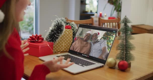 Běloška v Santa klobouku s videokalónem na notebooku doma o Vánocích. společenské distancování během covid 19 pandemie o Vánocích