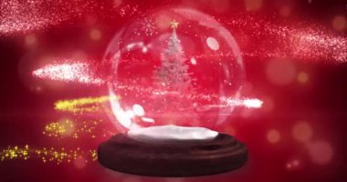 Kar küresindeki bir noel ağacının etrafında kayan yıldız kırmızı arka planda ışık lekeleriyle karşılaşıyor. Noel şenliği ve kutlama konsepti