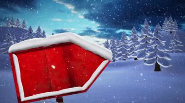 Kar, kırmızı tahta levha direğinin üzerine düşüyor ve kışın gökyüzüne karşı birden fazla ağaç düşüyor. Noel şenliği ve kutlama konsepti