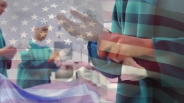 Ameliyathanede cerrahların üzerinde sallanan ABD bayrağının animasyonu. küresel tıp, covid 19 pandemik konsept sırasında sağlık hizmetleri dijital olarak üretilen video.