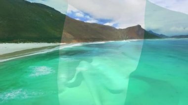 Plaj ve deniz dalgalarının hava manzarasına karşı Nijerya bayrağı sallamanın dijital bileşimi. Ulusal turizm ve seyahat kavramı