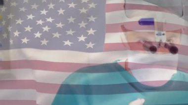 Ameliyathanede cerrahların üzerinde bayrak sallayan Amerikan bayrağı animasyonu. küresel tıp, covid 19 pandemik konsept sırasında sağlık hizmetleri dijital olarak üretilen video.