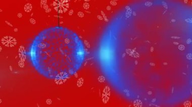 Birden fazla mavi Noel süslemesi üzerine düşen kar taneleri kırmızı arka planda asılı duruyor. Noel indirimi ve indirim konsepti