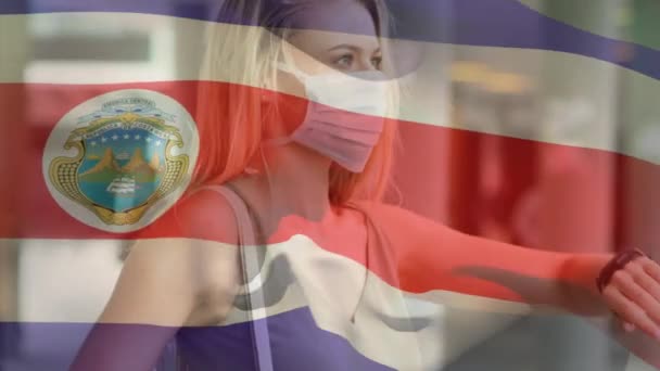 流行期にフェイスマスクを着用した女性に手を振るコスタリカの国旗のアニメーション 世界中で流行している19の概念をデジタルで — ストック動画