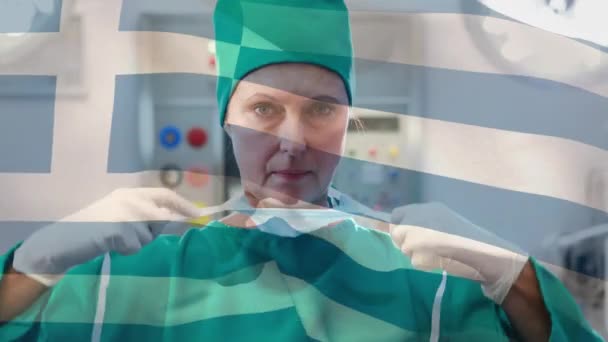 手术室里 在女外科医生面前挥动希腊国旗的动画 全球医学 围产期保健服务 数码制作的19种流行病概念视频 — 图库视频影像