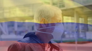 Covid 19 salgını sırasında yüz maskesi takan adamın üzerinde sallanan Kolombiya bayrağı animasyonu. küresel covid 19 salgın konsepti dijital olarak oluşturulmuş video.