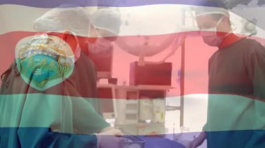 Kosta Rika bayrağının ameliyathanede cerrahların üzerinde dalgalanması. küresel tıp, covid 19 pandemik konsept sırasında sağlık hizmetleri dijital olarak üretilen video.