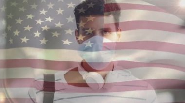Amerikan bayrağının, covid 19 salgını sırasında yüz maskesi takan adamın üzerinde dalgalanması. küresel covid 19 salgın konsepti dijital olarak oluşturulmuş video.