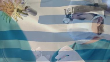 Ameliyathanede cerrahların üzerinde sallanan uruguay bayrağının animasyonu. küresel tıp, covid 19 pandemik konsept sırasında sağlık hizmetleri dijital olarak üretilen video.