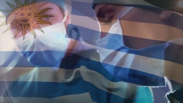 手術室で外科医に手を振っているウルグアイの旗のアニメーション 世界中の医療や医療サービスをデジタル化し — ストック動画