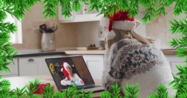 Zielone Gałęzie Nad Kobietą Noszącą Czapkę Mikołaja Nagrywającą Wideo Laptopie — Wideo stockowe