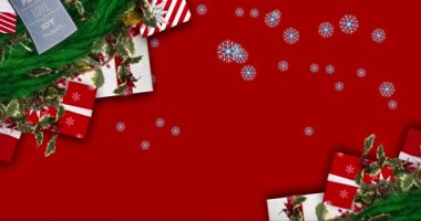 Noel çelengi üzerine düşen kar taneleri ve kırmızı arka planda hediyeler. Noel şenliği ve kutlama konsepti