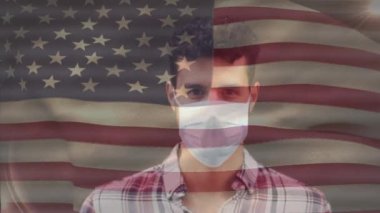 Amerikan bayrağının, covid 19 salgını sırasında yüz maskesi takan adamın üzerinde dalgalanması. küresel covid 19 salgın konsepti dijital olarak oluşturulmuş video.