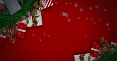 Noel çelengi üzerine düşen kar taneleri ve kırmızı arka planda hediyeler. Noel şenliği ve kutlama konsepti