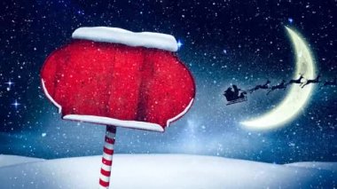 Kış manzarasında kırmızı ahşap tabela direğinin üzerine yağan kar gece gökyüzünde aya çarpıyor. Noel şenliği ve kutlama konsepti
