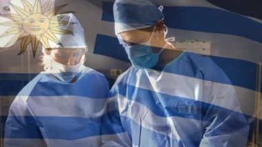 Ameliyathanede cerrahların üzerinde sallanan uruguay bayrağının animasyonu. küresel tıp, covid 19 pandemik konsept sırasında sağlık hizmetleri dijital olarak üretilen video.