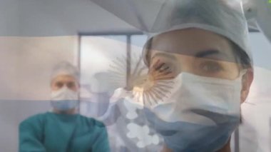 Ameliyathanede cerrahların üzerinde sallanan Arjantin bayrağının animasyonu. küresel tıp, covid 19 pandemik konsept sırasında sağlık hizmetleri dijital olarak üretilen video.