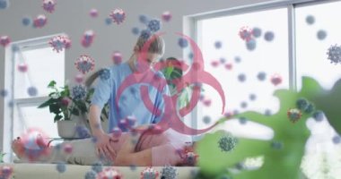 Biyolojik tehlike sembolü ve kovid 19 hücreleri yaşlı kadını tedavi eden kadın sağlık çalışanlarına karşı yüzüyor. Coronavirus covid-19 salgın konsepti