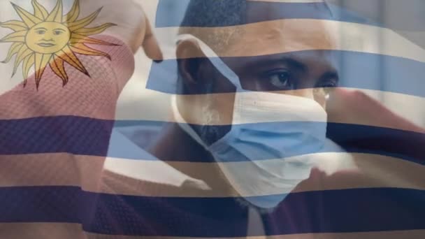 Animation Flaggan Uruguay Viftar Över Mannen Bär Ansiktsmask Covid Pandemi — Stockvideo