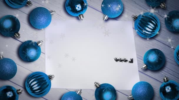 紙と複数の青いボールの上にリニア人によって引っ張られているそりでサンタクラスの上の雪の結晶 クリスマス フェスティバルとお祝いのコンセプト — ストック動画