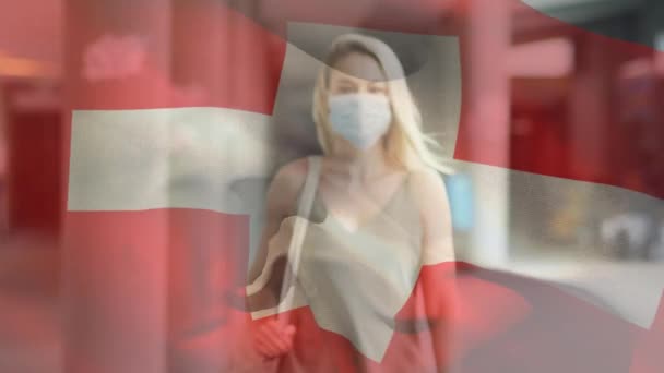 流行期に顔のマスクを着用した女性に手を振るスイスの国旗のアニメーション 世界中で流行している19の概念をデジタルで — ストック動画