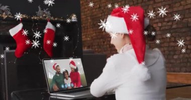 Noel 'de dizüstü bilgisayardaki video görüntülerinde beyaz şapkalı kızın üzerine kar yağması. Noel, gelenek ve kutlama konsepti dijital olarak oluşturuldu.