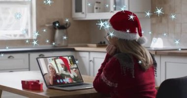 Noel 'de dizüstü bilgisayarda beyaz şapkalı bir kadının üzerine kar yağması. Noel, gelenek ve kutlama konsepti dijital olarak oluşturuldu.