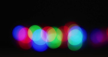 Siyah arka planda birden fazla renkli ışık yanıp sönüyor. Yılbaşı partisi şenlik kutlaması konsepti dijital olarak oluşturuldu.