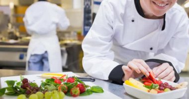 Gülümseyen beyaz kadın şef önlük giyip profesyonel mutfakta yemek hazırlıyor. Mutfak, yemek hazırlama ve yemek servisi..