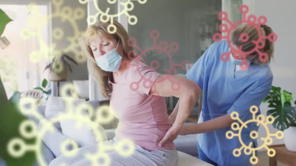 白人のシニア女性と看護師の顔マスクマッサージを身に着けている上のCovidウイルス細胞のアニメーション 世界中で流行している19の概念をデジタルで — ストック動画