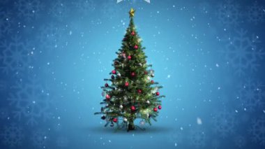 Noel süslemeleri asılıyor ve mavi arka planda dönen Noel ağacının üzerine kar yağıyor. Noel şenliği ve kutlama konsepti